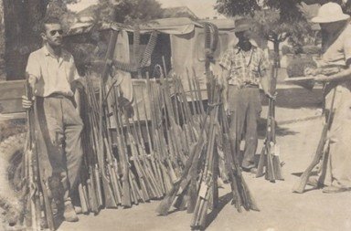 Henrique Luiz Roessler à direita, anotando dados junto a armas e munições apreendidas de caçadores ilegais em 1954.