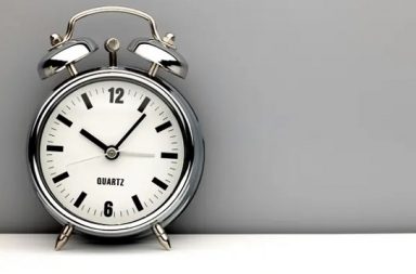 A retro chrome alarm clock on a grey background, symbolizing time management and the limits of personal action.