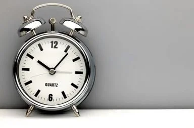 A retro chrome alarm clock on a grey background, symbolizing time management and the limits of personal action.