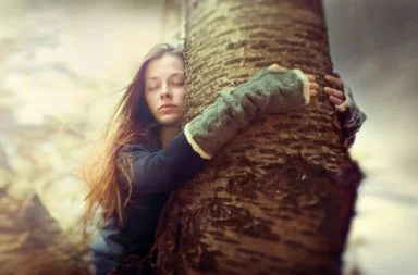 Mulher de olhos fechados a abraçar uma árvore, simbolizando a paz e o verdadeiro amor na teosofia.
