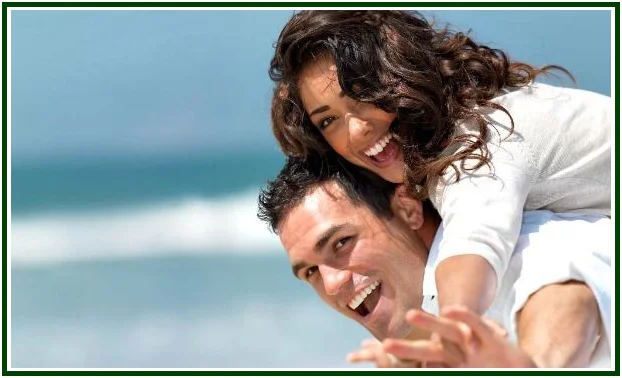 Casal sorridente na praia em harmonia, simbolizando a união nos planos da alma eterna e da inteligência universal.