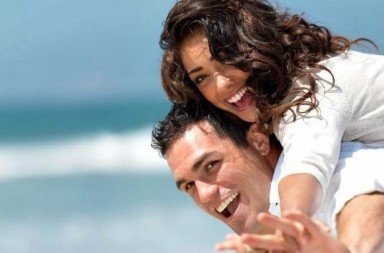 Casal sorridente na praia em harmonia, simbolizando a união nos planos da alma eterna e da inteligência universal.