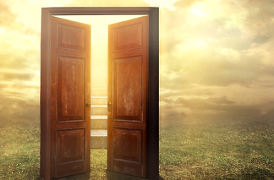 Uma grande porta de madeira escura aberta no meio de um campo de relva, revelando degraus de uma escadaria banhada por uma luz solar dourada e intensa entre nuvens, simbolizando a nova primavera espiritual e a renovação de Adyar.