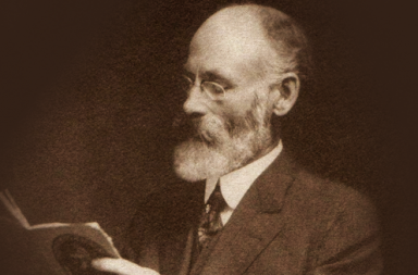 Historical sepia portrait of Robert Crosbie with a white beard and glasses, looking down while reading a small open book.