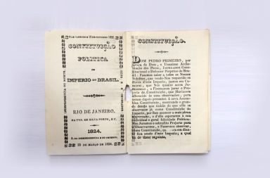 Livro aberto exibindo as páginas amareladas da Constituição Política do Império do Brasil de 1824, impressa no Rio de Janeiro, contendo a declaração de Dom Pedro Primeiro sobre as leis e a estrutura do Estado que servem de base para o debate sobre a ética na política nacional.