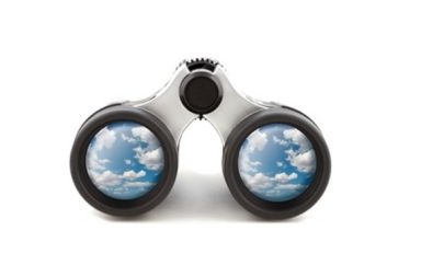 Vista frontal de uns binóculos modernos com detalhes prateados e pretos, exibindo em ambas as lentes o reflexo nítido de um céu azul com nuvens brancas, simbolizando a claridade mental obtida através da atenção.