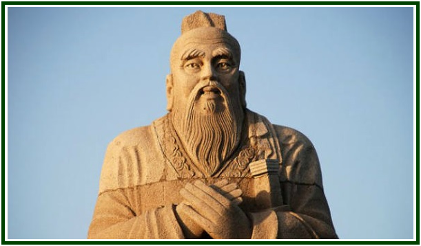 Plano médio da colossal estátua de pedra de Confúcio com longas barbas e mãos cruzadas sobre o peito, cuja sabedoria tradicional está preservada nos analectos, isolada contra um fundo de céu azul limpo.