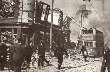 Destruição urbana em Londres com pessoas entre escombros e um autocarro de dois andares durante a Segunda Guerra Mundial.