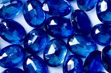 Close-up photograph of several faceted blue gemstones, representing the esoteric meaning of sapphire.