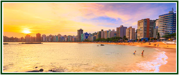 Fotografia de uma praia urbana com prédios ao fundo durante o pôr do sol, ilustrando a jornada de descoberta na teosofia.