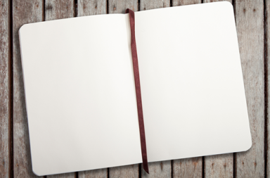 Caderno aberto com páginas totalmente em branco e fita marcadora vermelha sobre uma mesa de madeira, evocando o aprendizado no silêncio.