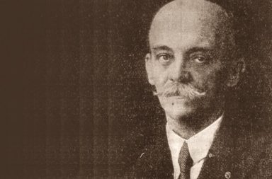 Retrato histórico em tom sépia de Raymundo Pinto Seidl, pioneiro do movimento teosófico no Brasil, de fato, gravata e bigode proeminente.