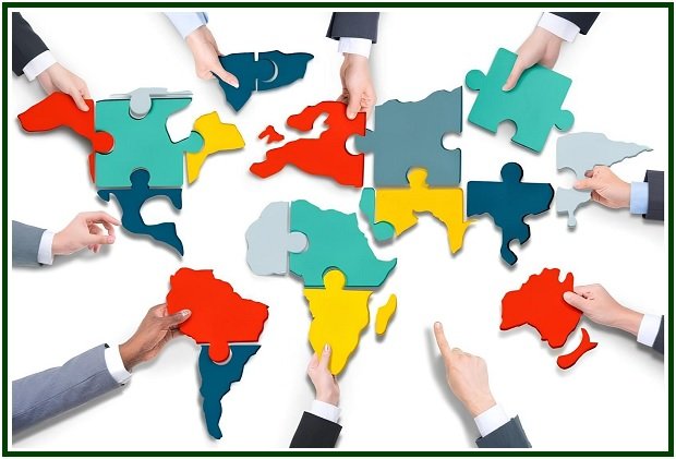 Várias mãos de diferentes tons de pele encaixando peças de puzzle coloridas que formam o mapa-múndi sobre um fundo branco com uma moldura verde.