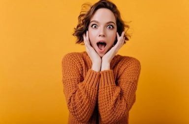 Young woman with a shocked facial expression holding her face, illustrating if talking about theosophy shocks people.